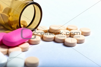 Medicine bottle against white isolated background with pills