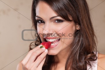 Pretty young woman eating a strawberry