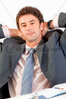 Pleased businessman relaxing on office armchair

