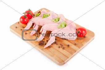 Raw chicken wings with condiments on chopping board 