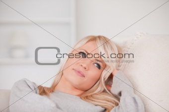 Portrait of a happy blonde woman relaxing while lying on a sofa
