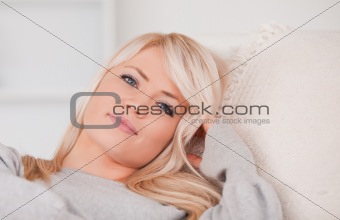 Portrait of a happy blonde woman lying on a sofa