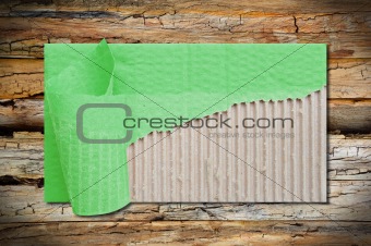 textured brown corrugated cardboard sheet with torn on wood background