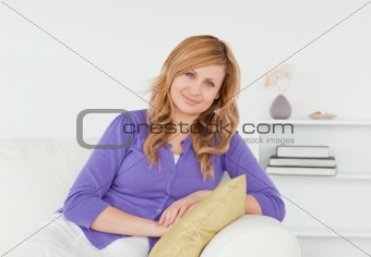 Beautiful red-haired woman posing while sitting on a sofa