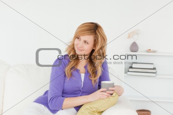 Pretty red-haired woman looking at something while sitting on a 