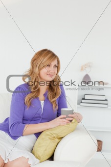 Pensive red-haired woman sitting on a sofa