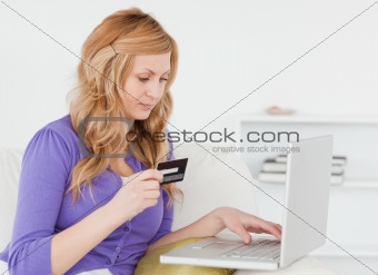 Careful woman sitting on a sofa is going to make a payment on th