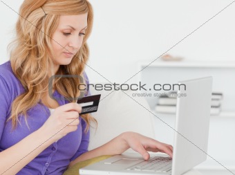 Concentrated woman sitting on a sofa is going to make a payment 