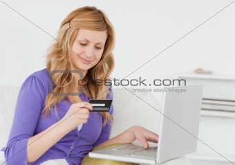 Attractive woman sitting on a sofa is going to make a payment on