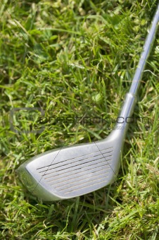Golf club driver laying in grass, concept photography