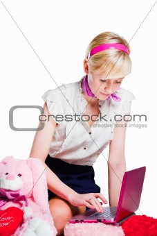 beautiful blond girl working with pink laptop on isolated white