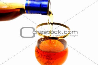 Bottleneck filling a glass with brown liquid