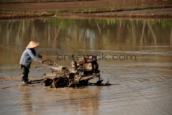 plough machine and farmer in the paddy field