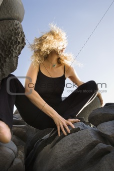 Woman crouching on rocks.