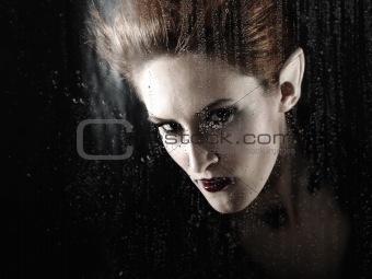 beautiful fashion vampire woman behind rainy window