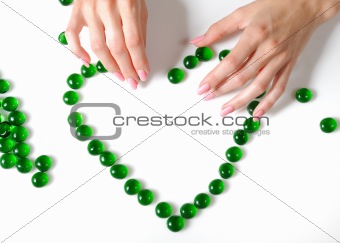 Beautiful hands building a heart sighn from green stones