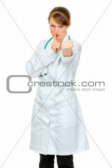 Angry  medical doctor woman with finger at mouth and threaten with fist
