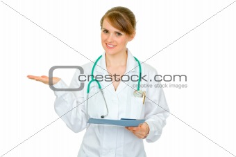Smiling doctor woman with medical chart presenting something on empty hand
