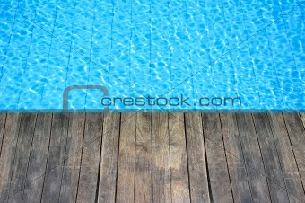 wood floor beside the blue swimming pool