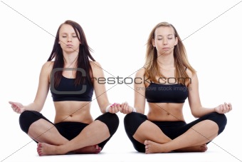 two young women sitting on the floor exercisng yoga - isolated on white