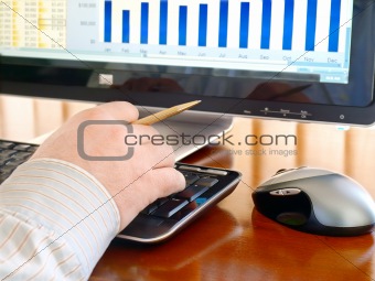 Man's hand with pen typing at a computer keyboard.