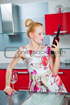 blonde girl with glass and bottle of wine in interior of red kitchen