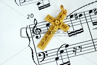A golden cross on the top of a music sheet