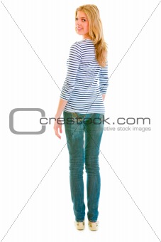 Full length portrait of smiling beautiful teen girl looking back over her shoulder
