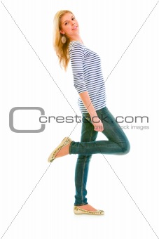 Full length portrait of smiling beautiful teen girl standing on one leg
