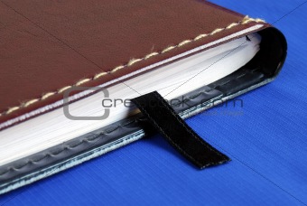 Brown notebook with a black bookmark isolated on bluedown the notes for the weekend isolated on blue