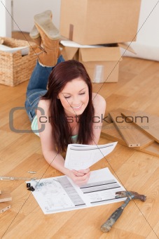 Good looking red-haired girl reading a manual before do-it-yours