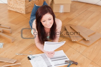 Pretty red-haired girl reading a manual before do-it-yourself wh