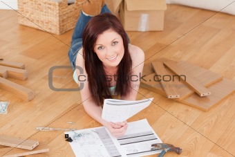 Pretty red-haired girl posing while reading a manual before do-i