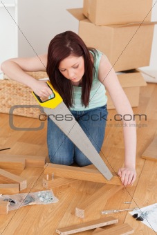 Beautiful red-haired woman using a saw