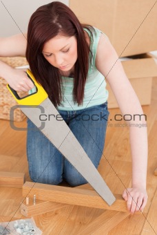 Attractive red-haired woman using a saw