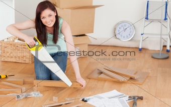 Pretty red-haired woman using a saw