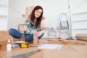 Attractive red-haired female nailing a plank at home