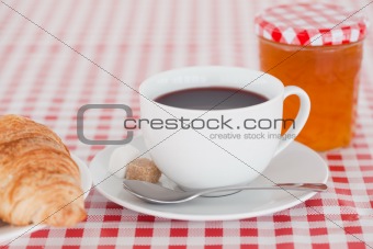 Continental breakfast with croissant, jam and coffee on a tablec