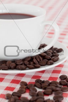 Coffee, saucer and beans on a tablecloth