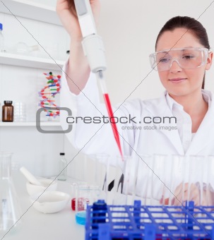 Cute female biologist holding a manual pipette with sample from 
