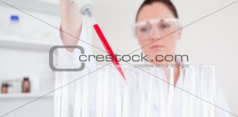 Beautiful red-haired scientist filling up a test tube