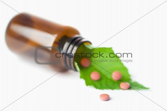 Leaf and pills in a small bottle