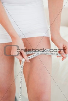 Young woman measuring her hip with a tape measure while standing