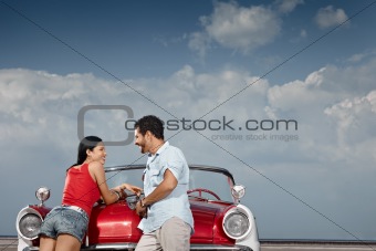 man and beautiful woman leaning on cabriolet car