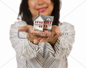 Attractive Multiethnic Woman Holding Out In Front of Her a Small House Isolated on a White Background.