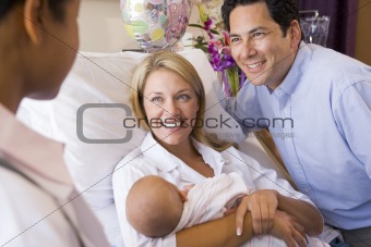 New parents with baby talking to doctor and smiling