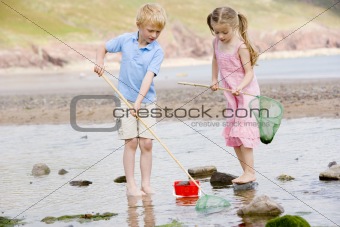 Brother and sister at beach with nets and pail