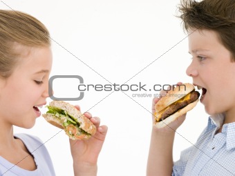 Sister eating apple by brother eating cheeseburger