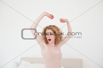 Good looking blonde female stretching in her bedroom