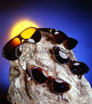 Four sunglasses over a nice stone